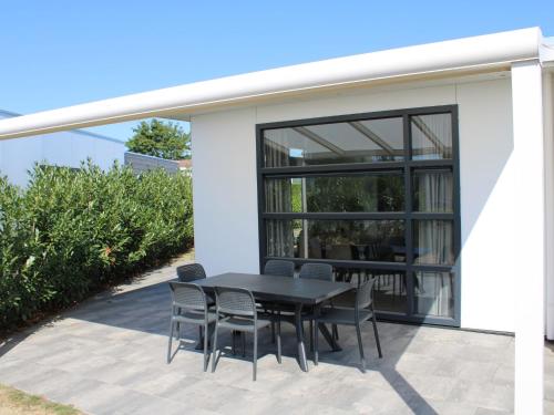 a patio with a table and chairs in front of a house at Modern chalet with a dishwasher in Lathum in Lathum