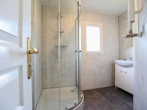 bagno con doccia in vetro e lavandino di Nice chalet in a holiday park directly on the recreational lake and the Veluwe a Lathum