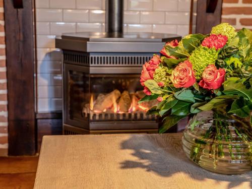 a vase of flowers on a table in front of a fireplace at Beautiful holiday home with hot tub in Losser