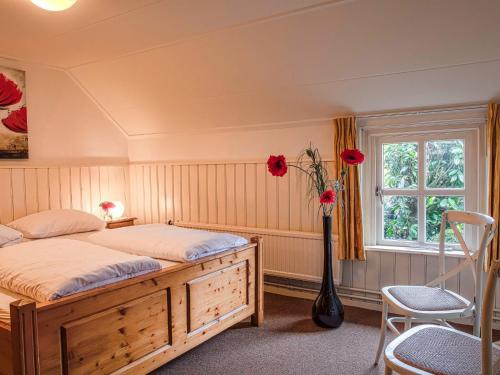 um quarto com uma cama e um vaso com rosas vermelhas em Beautiful group accommodation with hot tub and Finnish kota, located in Twente em Losser