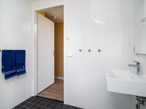 a bathroom with white walls and a sink and blue towels at Disabled house on the water, on a holiday park in Friesland in Akkrum