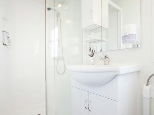 La salle de bains blanche est pourvue d'un lavabo et d'une douche. dans l'établissement Comfortable chalet 4 5 km from Rovinj, à Rovinj