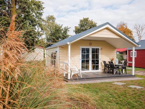 a cottage with a deck and a table and chairs at Covered Terrace Chalet at Leukermeer in Well