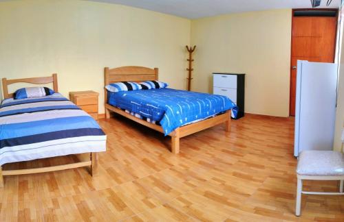 1 dormitorio con 2 camas y suelo de madera en Amachito's Casa Recreacional en Lima