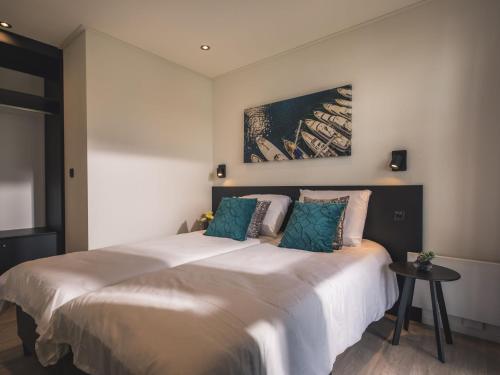 1 dormitorio con 1 cama grande con almohadas azules en Luxurious holiday home on the water in the Betuwe, en Maurik