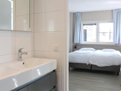 La salle de bains est pourvue d'un lavabo et d'un lit dans la chambre. dans l'établissement Wellness villa with sauna, at a holiday park on the water in Friesland, à Idskenhuizen