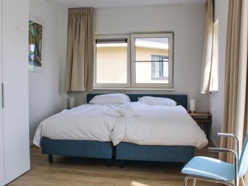 een slaapkamer met een groot bed en 2 ramen bij Atmospheric villa on the water, at a holiday park in Friesland in Idskenhuizen