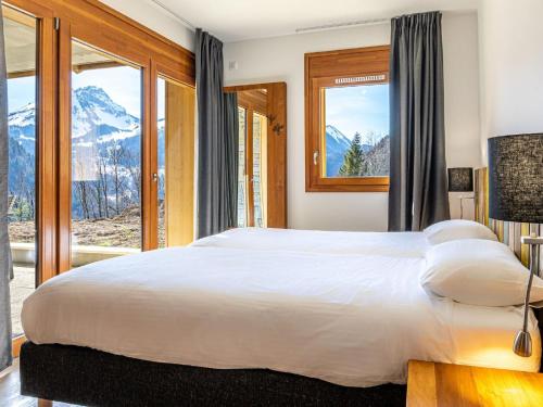 a bedroom with a large white bed and windows at Modern Mountain Stay in Abondance
