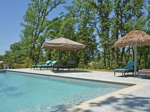 - une piscine avec 2 chaises longues et des parasols à côté de la piscine dans l'établissement Villa in Montauroux with Pool and Forest Views, à Montauroux