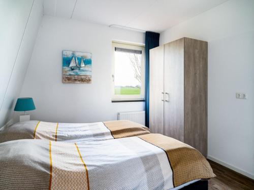 een slaapkamer met een bed en een raam bij Spacious holiday home with outdoor spa, on a holiday park in Friesland in Akkrum