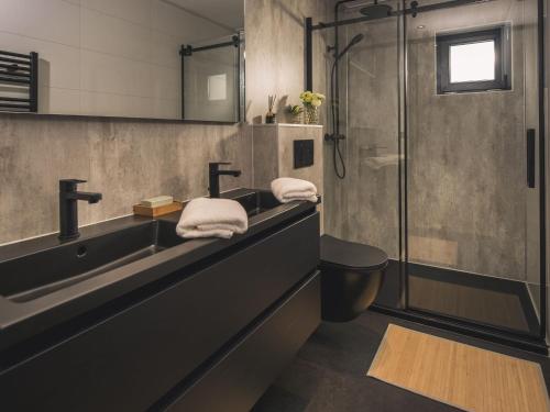 W łazience znajduje się umywalka oraz prysznic z ręcznikami. w obiekcie Luxurious holiday home nearby the Lower Rhine w mieście Maurik