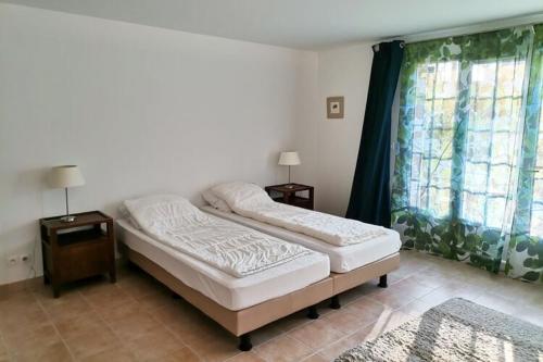 1 dormitorio con 2 camas y ventana en Detached villa with large garden near beautiful golf course, en Vasles