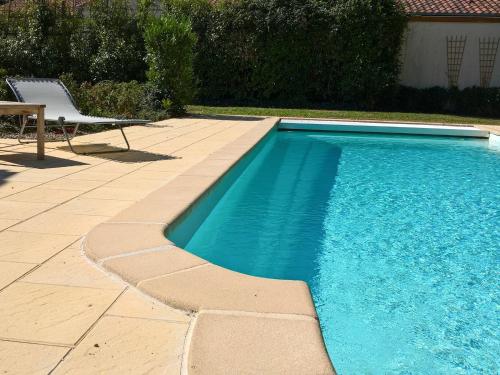 a swimming pool with a bench and a chair next to it at Villa with garden near beautiful golf course in Vasles