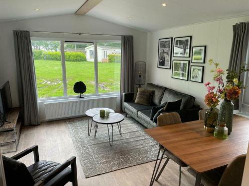 a living room with a couch and a table at Comfort chalet on a recreational lake in Lathum