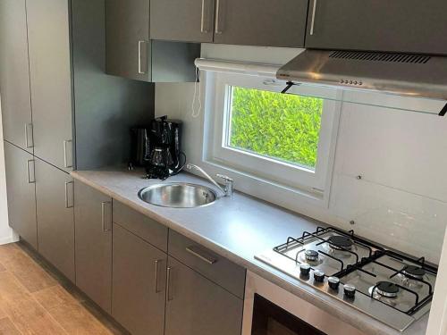 a kitchen with a sink and a stove and a window at Comfort chalet on a recreational lake in Lathum