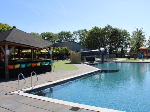a swimming pool with a slide and a playground at Comfort chalet on a recreational lake in Lathum