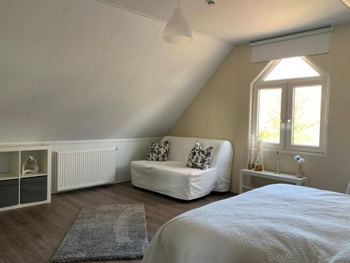 a bedroom with a white bed and a window at Holiday home in a holiday park directly on the recreational lake and the Veluwe in Lathum