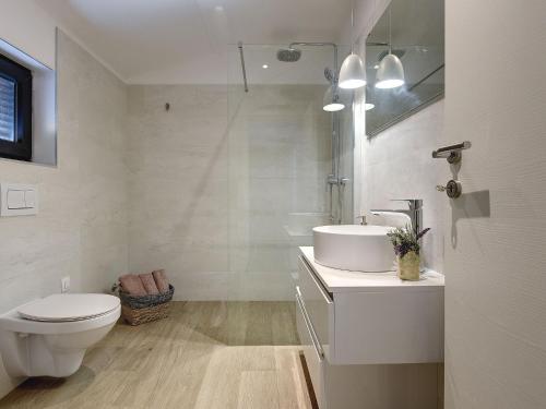 a white bathroom with a toilet and a sink at Modern villa swimming pool , outdoor kitchen and fenced garden in Pula