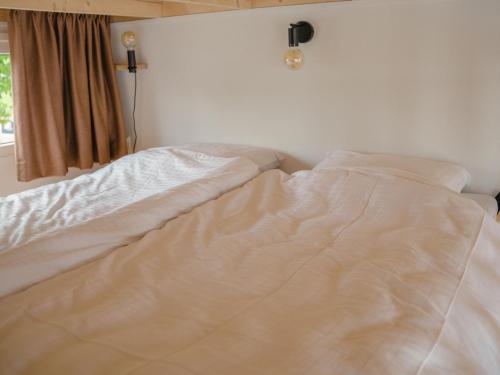 an unmade bed in a bedroom next to a window at Tiny House by Dutch Waterfront Retreat in Maurik