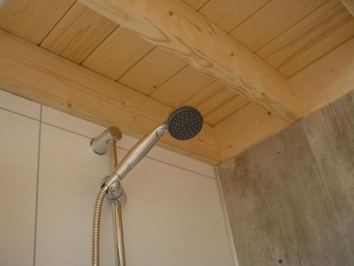 a shower head in a bathroom with a wooden ceiling at Cozy tiny house on the water, located in a holiday park in the Betuwe in Maurik