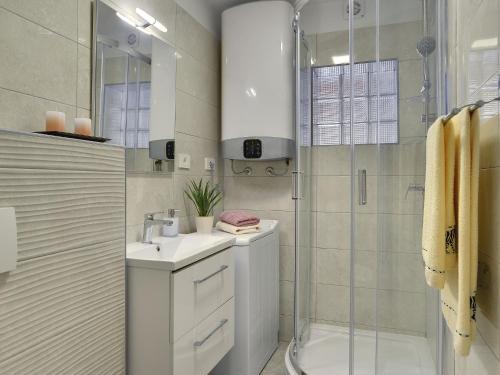 uma casa de banho branca com um chuveiro e um lavatório. em Detached house with private pool, 15 minutes drive from the coast em Vodnjan