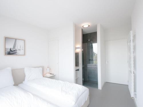 a white bedroom with a bed and a walk in shower at Modern design lodge directly at the water, in national park in Tholen