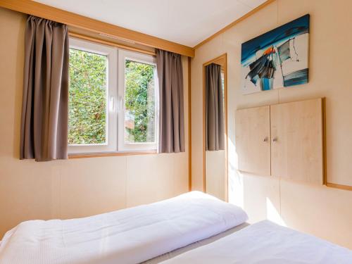 1 dormitorio con 2 camas y 2 ventanas en Nice chalet in a holiday park with swimming pool, on the Leukermeer, en Well
