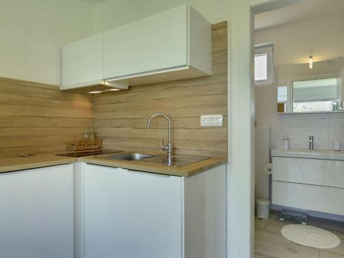 a kitchen with white cabinets and a sink at Modern, detached holiday home with enclosed garden, near the centre and the beach in Fažana