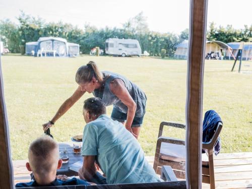 a woman standing over a picnic table with two men at Tent Lodge in Nommern near Forest in Nommern