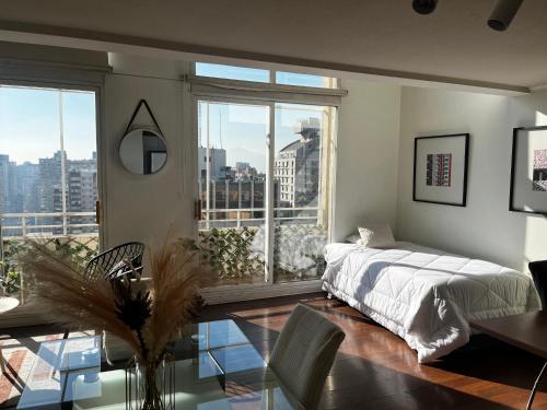 um quarto com uma cama, uma mesa e janelas em Suite on the top em Santiago
