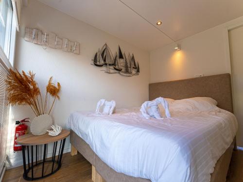 um quarto com uma cama com lençóis brancos e veleiros na parede em Lush houseboat with roof terrace in Lemmer em Lemmer
