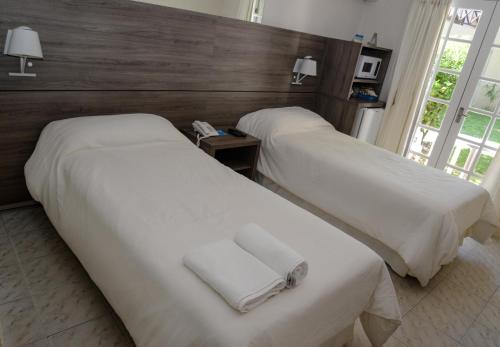 2 camas en una habitación de hotel con sábanas blancas y toallas en Solanas Punta Del Este Spa & Resort, en Punta del Este