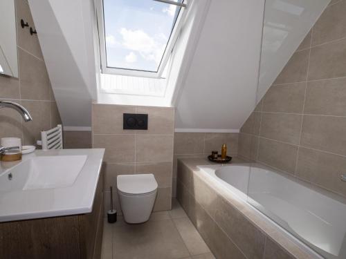 La salle de bains est pourvue d'une baignoire, d'un lavabo et d'une fenêtre. dans l'établissement Beautiful villa on the water, on a holiday park in Friesland, à Sint Nicolaasga