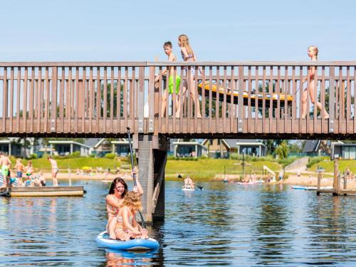 a woman and a child on a paddle board in the water at Chalet with covered terrace in the Leukermeer in Well
