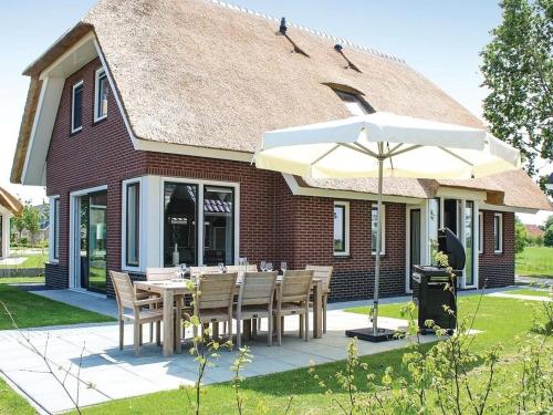 a table with chairs and an umbrella in front of a house at Villa in Friesland with Sauna and Jetty in Idskenhuizen
