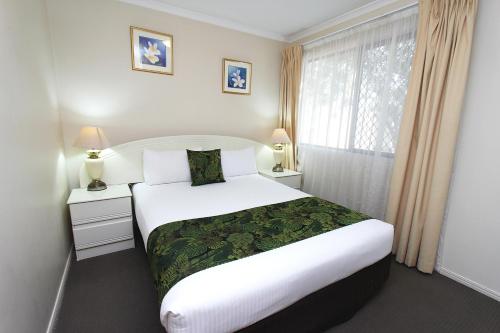 Un dormitorio con una gran cama blanca y una ventana en The Palms Motel en Chinchilla