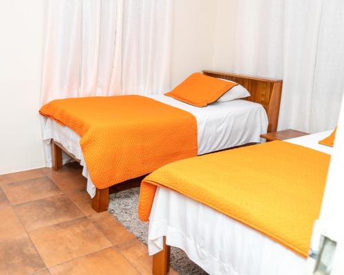 two beds with orange and white sheets in a room at Francis Nook Bourg Mulatresse Room in San Juan
