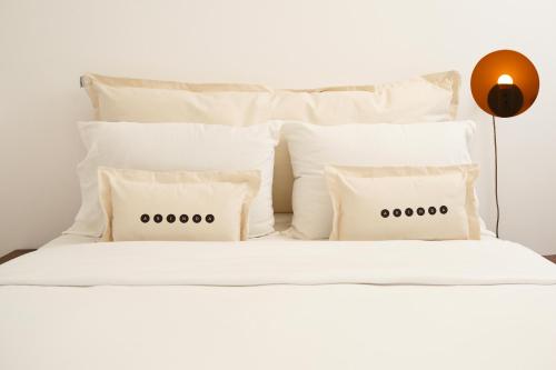 a white bed with white pillows and a lamp at Tabas - Edifício Arinda - São Paulo in Sao Paulo