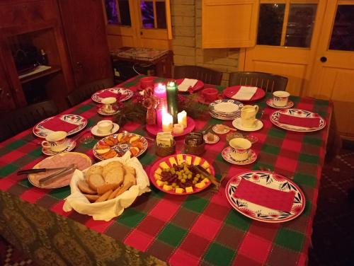 a table with a red and green table cloth with food and candles at Mi Casa es tu Casa Inn in Chiquinquirá