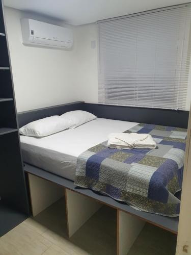 um quarto com uma cama com um cobertor e uma janela em Apartamento 509 Gravataí em Gravataí
