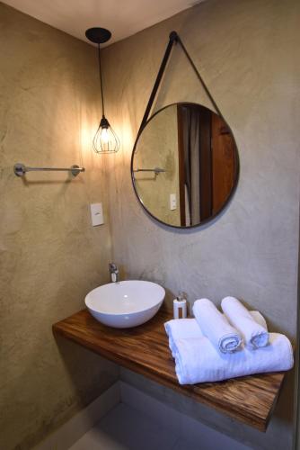 a bathroom with a sink and a mirror and towels at Pousada Villa Manso in Conceição da Ibitipoca