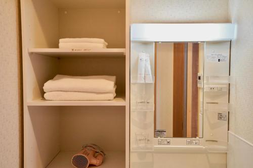 a cupboard with towels and a mirror in a bathroom at Nenenomichi in Kyoto