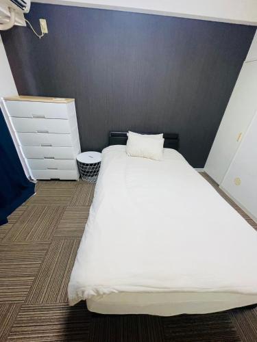 a bedroom with a white bed and a gray wall at SUNPIA WOMBLE GATE l 大滝町 in Kusugaurachō