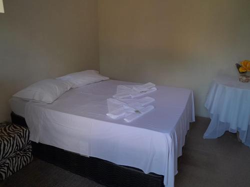 Una cama con sábanas blancas y toallas blancas. en Espaço Bella Ville, en Caparaó Velho