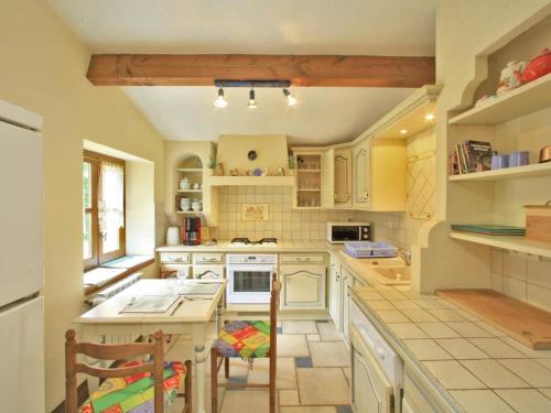 une cuisine avec des armoires blanches et une table et des chaises dans l'établissement Maison Périgourdine restaurée avec jardin, proche Sarlat, étang de pêche et vélos électriques fournis - FR-1-616-145, à Proissans