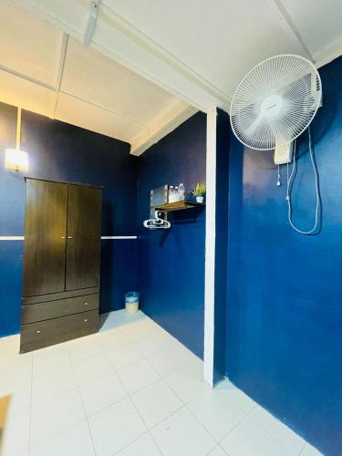 a room with a blue wall and a fan at Vintage Guesthouse in Tanah Rata