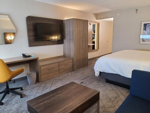 um quarto de hotel com uma cama, uma secretária e uma televisão em Holiday Inn Express Fort Lauderdale North - Executive Airport, an IHG Hotel em Fort Lauderdale