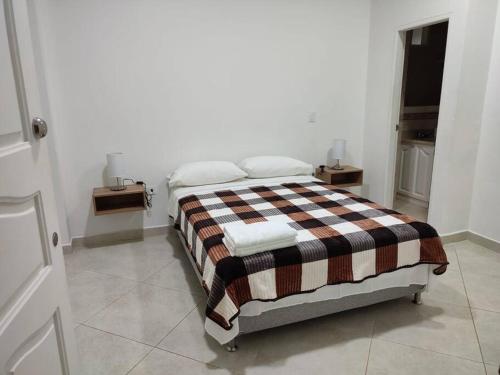 a bed in a white room with two night stands at Hermosa Casa para compartir en Familia y amigos in Jericó