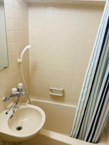 a bathroom with a sink and a shower curtain at SUNPIA WOMBLE GATE l 大滝町 in Kusugaurachō