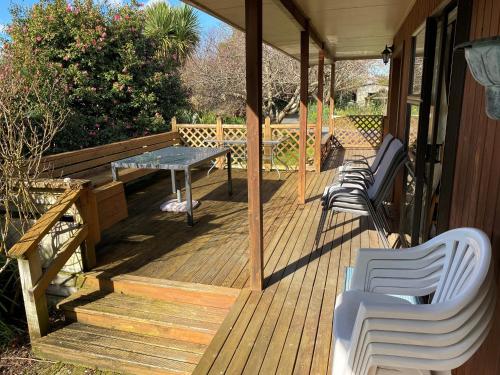 a wooden porch with chairs and a table on it at Chris's Cabin in Greytown